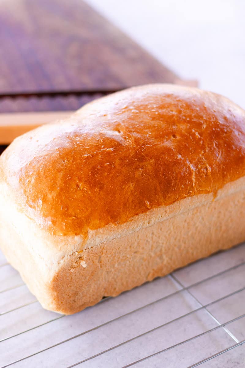 Golden brown loaf bread on a cooling rack.