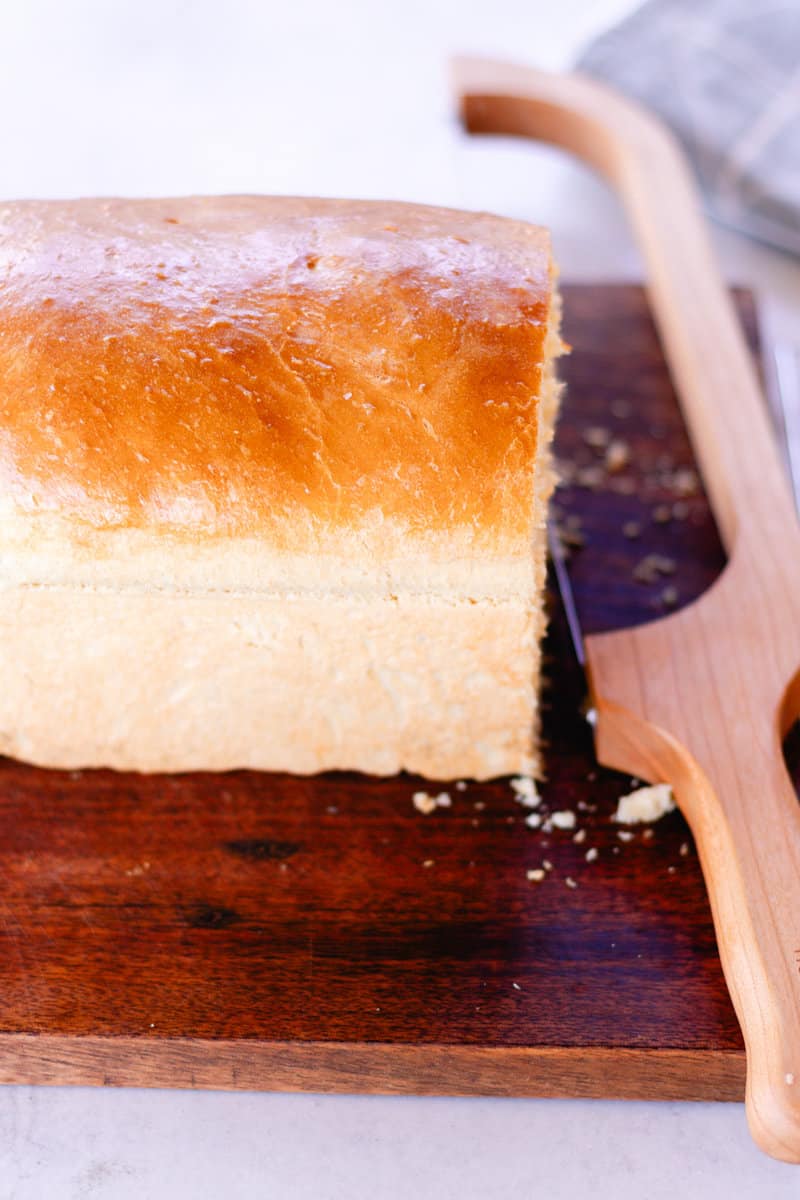 Cast iron loaf bread on a wooden cutting board with a bread knife next to it.