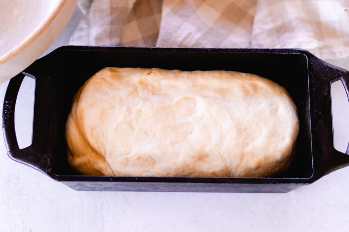 Bread in a cast iron loaf pan that is not quite cooked.