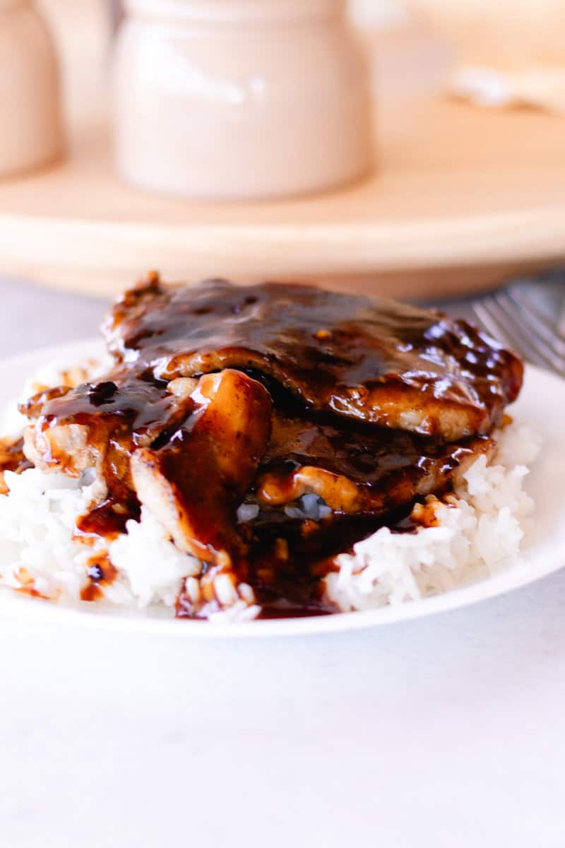 A bed of white rice serves as the base for Korean beef brisket, which is topped with a creamy sauce.