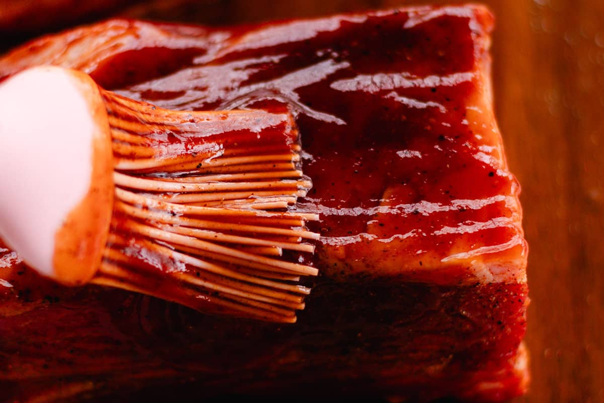 Brushing ribs with bbq sauce.