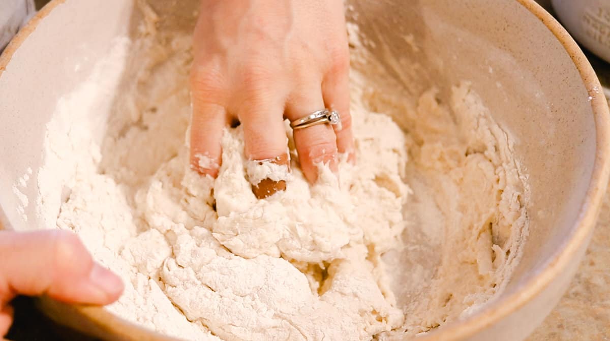 Kneading the dough in a mixing bowl by hand.