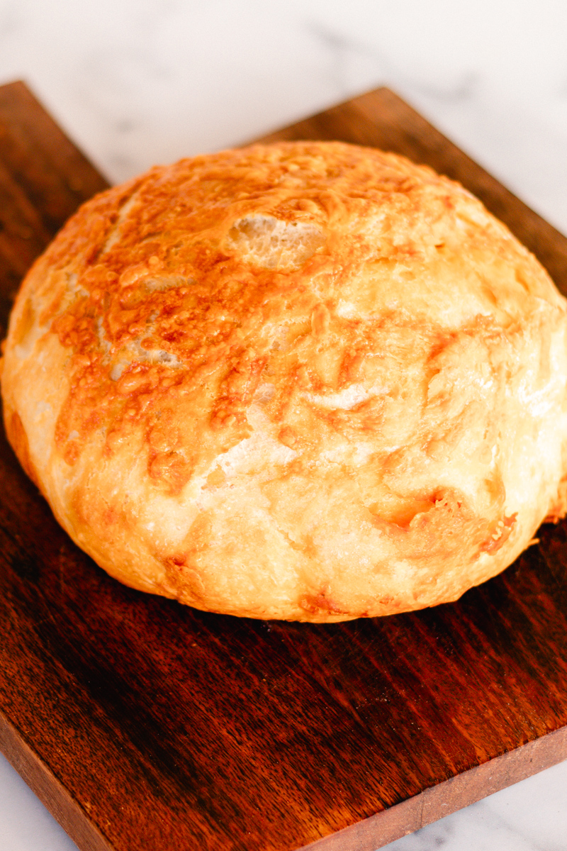 Golden brown dutch oven bread on a wooden table.