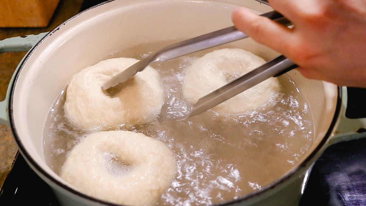 Boiling the bagels in water with sugar and baking soda. 