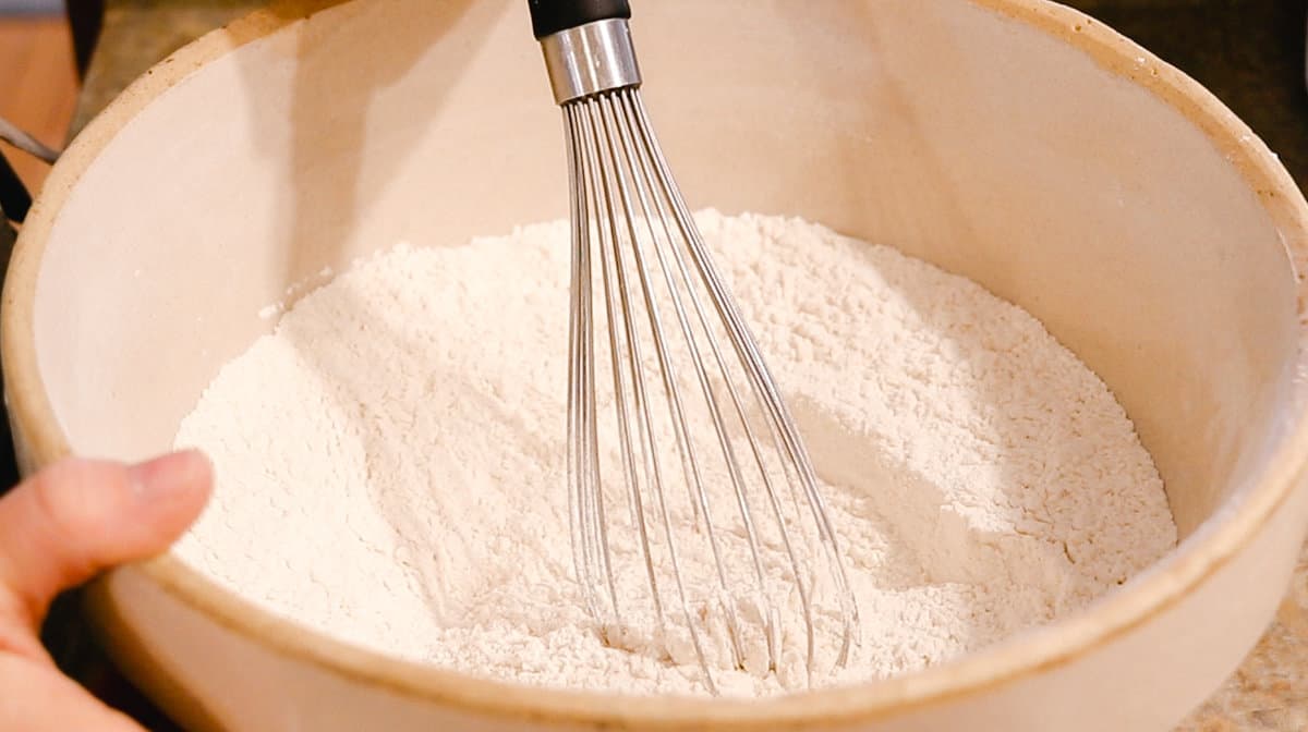 Whisking together flour, salt, sugar and  dried onion flakes in a glass bowl.