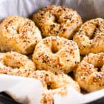 Greek yogurt bagels with no yeast cooling on parchment paper and topped with everything bagel seasoning.