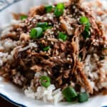 A heaping plate of sweet and spicy shredded chicken on top of white rice.