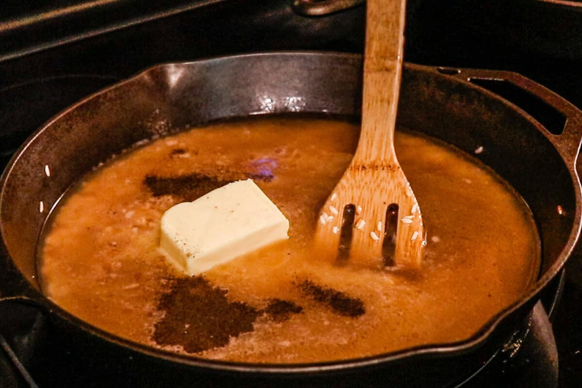 Adding the remaining ingredients to the skillet with the rice and stirring with a wooden spatula.