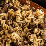 Beef tips and noodles in a cast iron skillet.