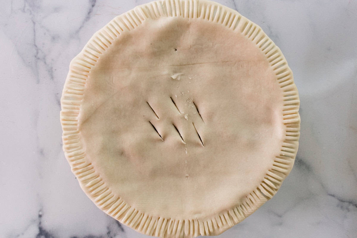 Laying on the top crust and crimping the edges and cutting a few small slits into the middle for steam to escape.