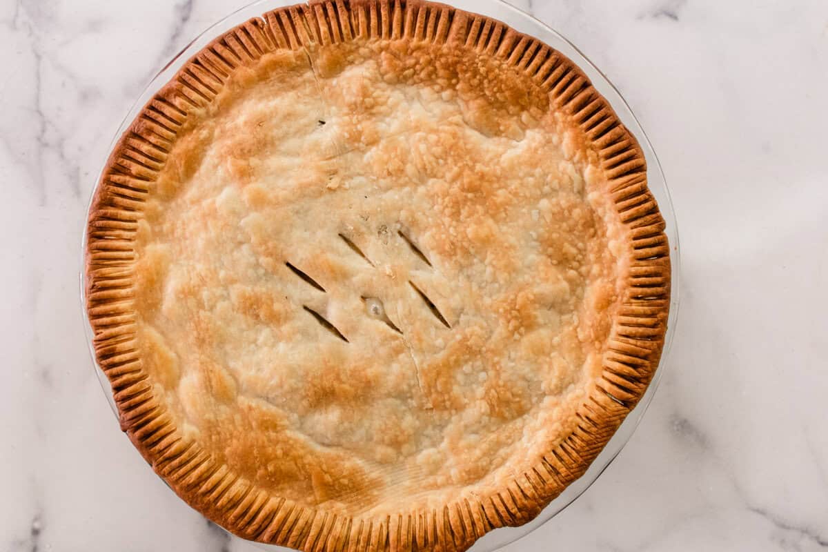 A baked chicken pot pie on a marble countertop.
