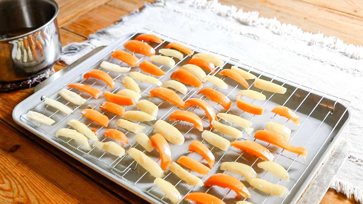Drying the fruit peels on a rack before tossing in the sugar and citric acid mixture.
