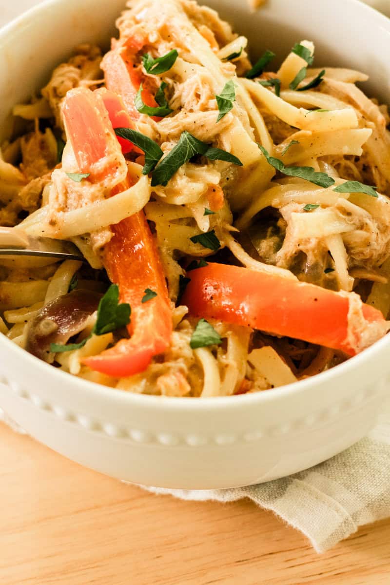 Cajun chicken pasta in a white bowl on a wooden table.