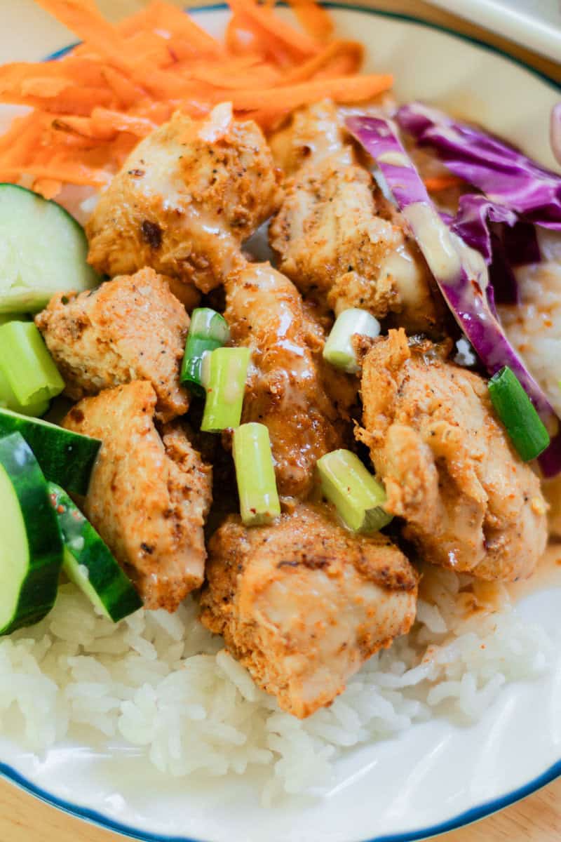Bang bang chicken with brightly colored fresh vegetables and a steaming bed of rice.