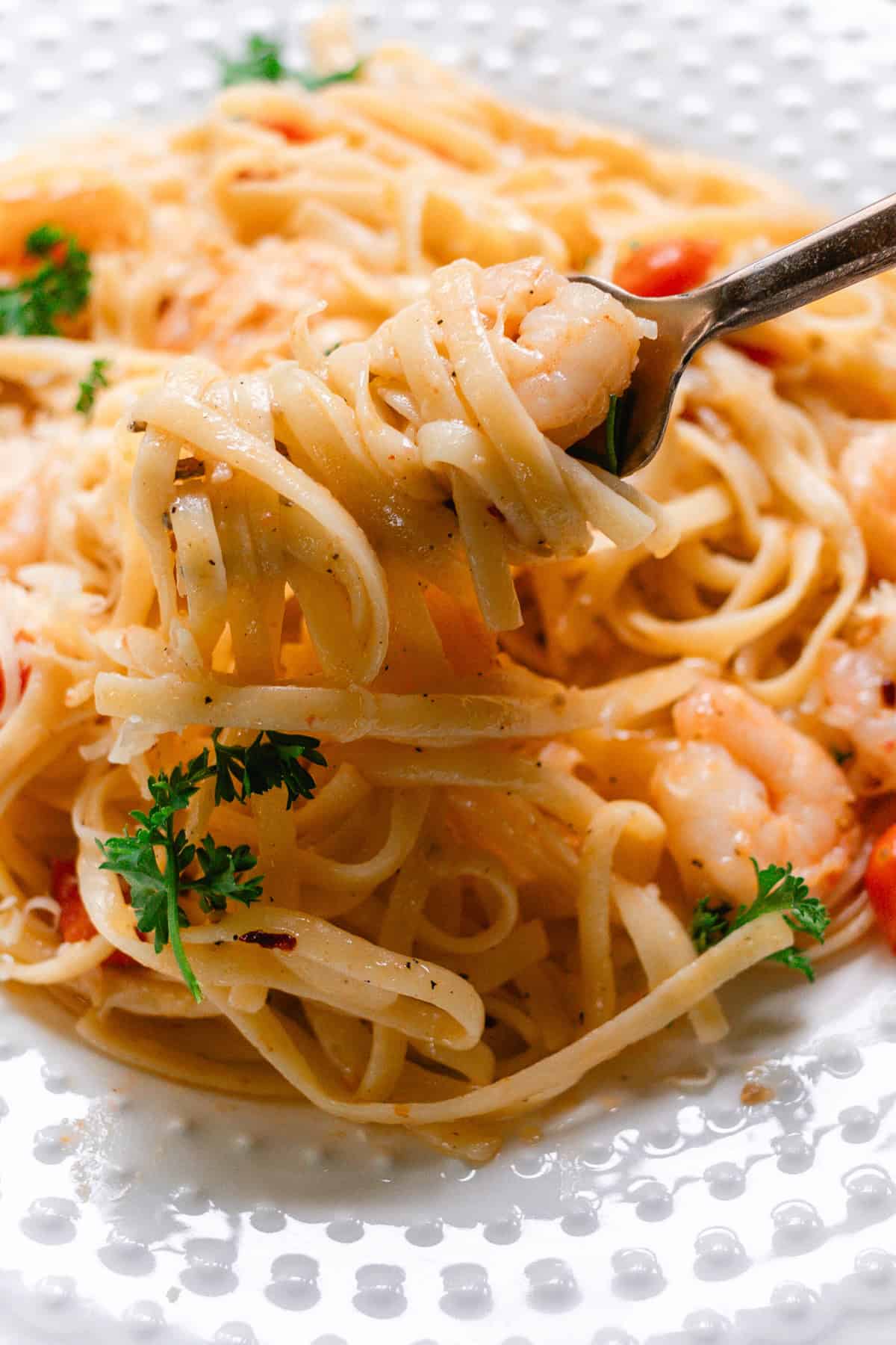 Twirling up the shrimp and pasta on a fork.
