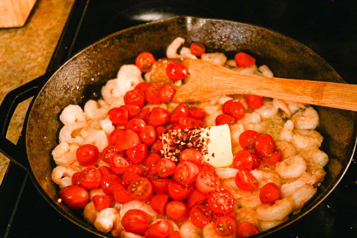 Melting butter in the skillet with the shrimp along with cherry tomatoes and spices. 