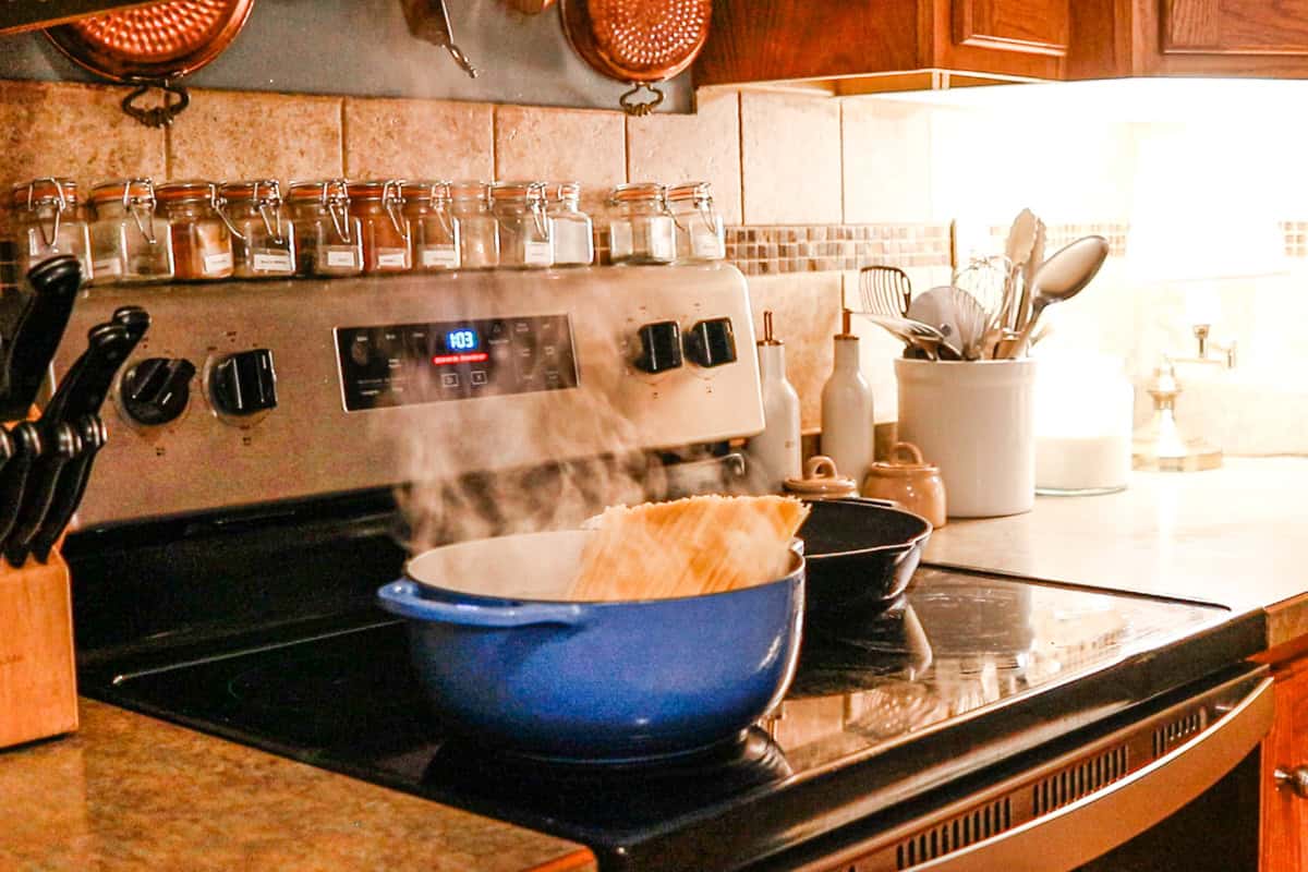 Boiling water in a blue dutch oven with pasta noodles.