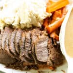 Platter of sliced rump roast, carrots, mashed potatoes, and gravy.