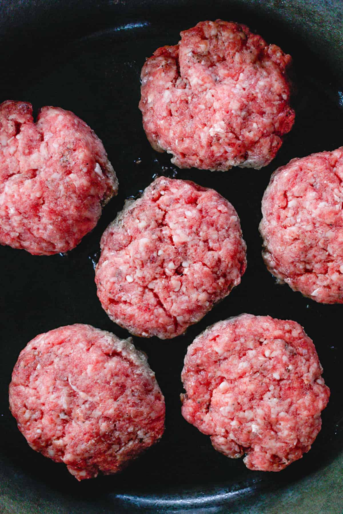 Cooking the burgers on a cast iron skillet.