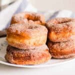 Homemade cinnamon sugar donuts on white plate.