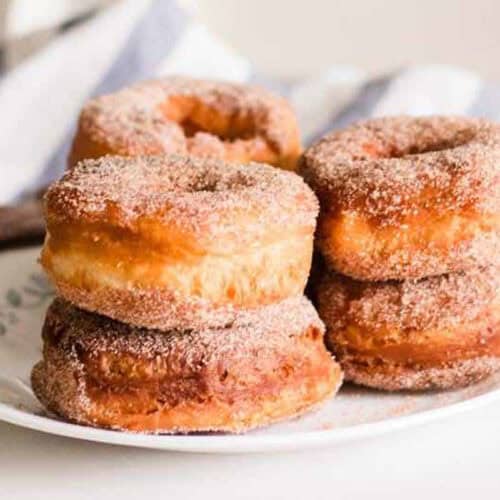 Homemade cinnamon sugar donuts on white plate.