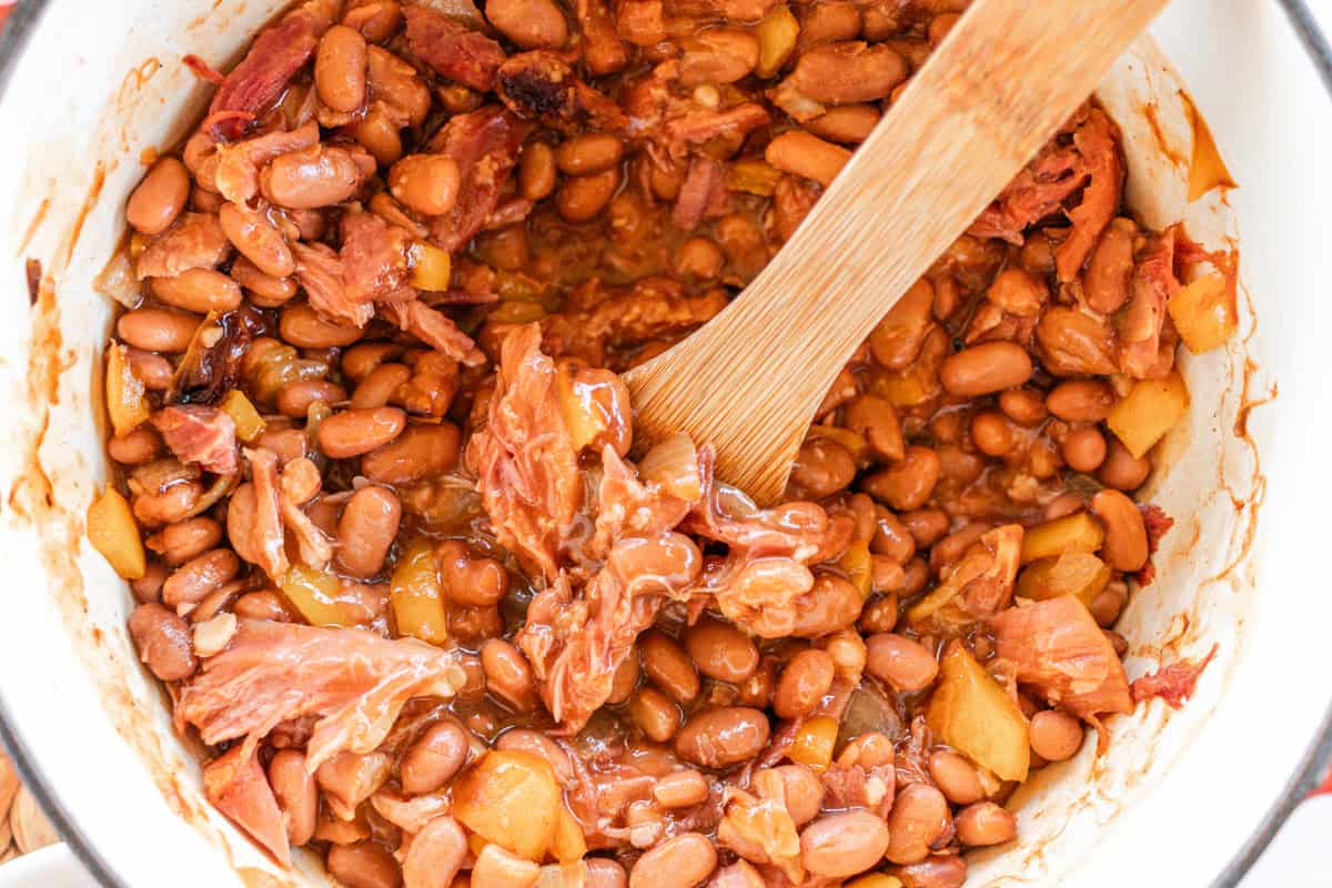 Dutch oven baked beans in a large pot with chunks of ham hock.