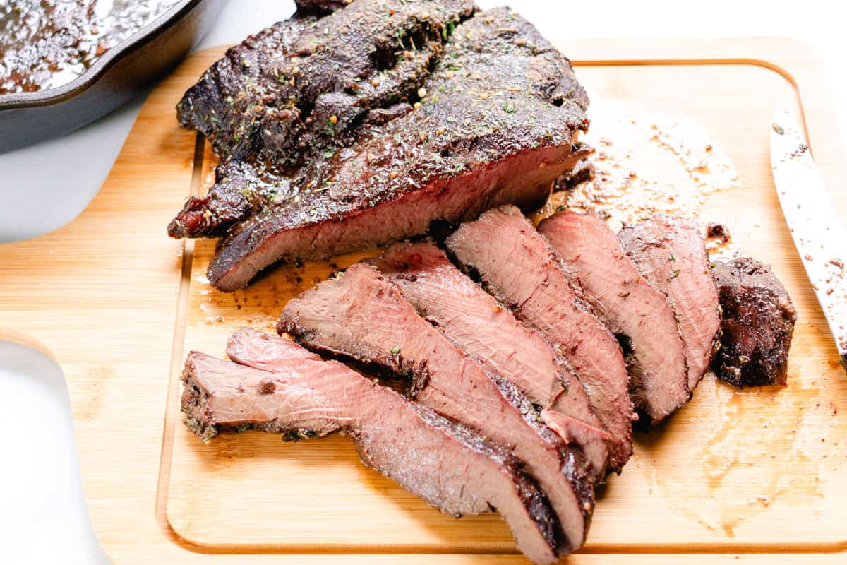 Oven roasted beef heart resting on a cutting block.