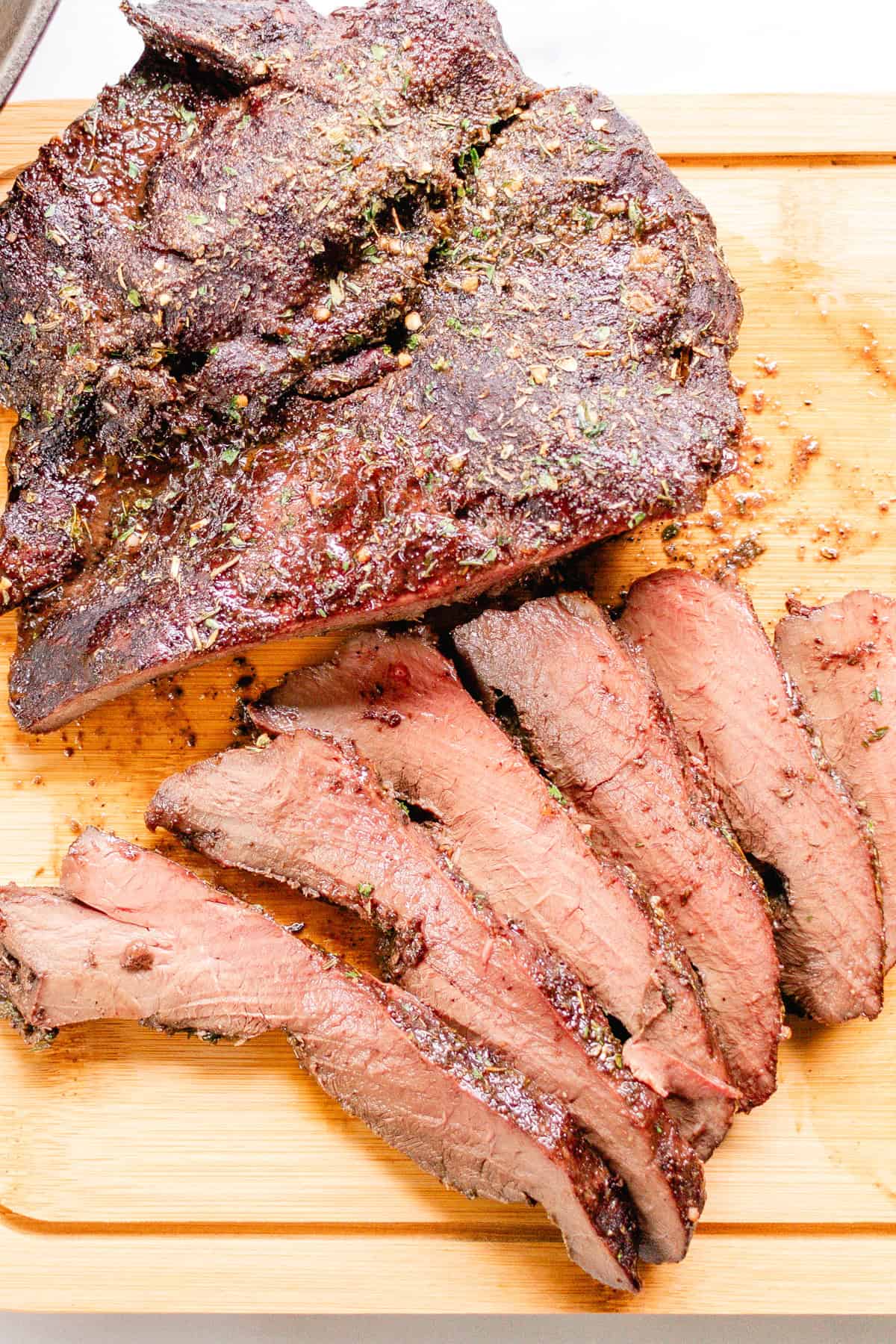 Thinly sliced roast beef heart on a wooden cutting board. 