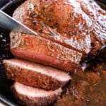 Slicing the roast with a sharp knife against the grain.