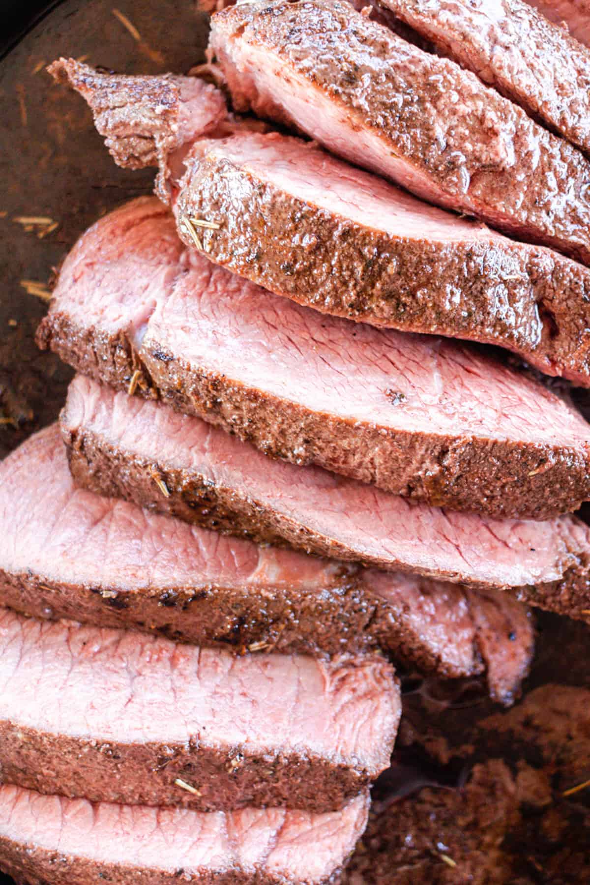 Sirloin tip roast cut into serving sized pieces in a cast iron skillet.