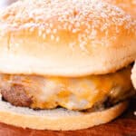 Venison burger with melted cheese on a sesame seed bun.