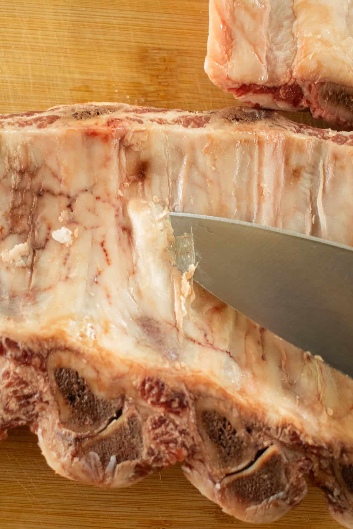 A knife cutting the membrane from the back of the ribs. 