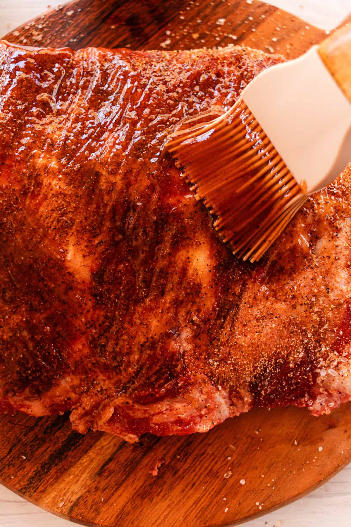 A barbecue brush brushing on barbecue sauce onto the ribs. 