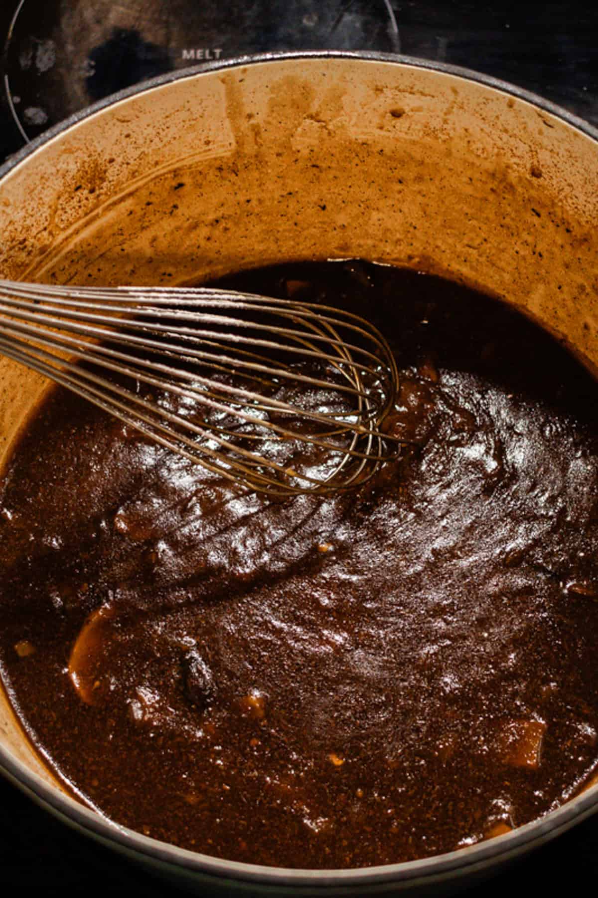 Whisking the gravy with a wire whisk as it thickens on the stovetop. 