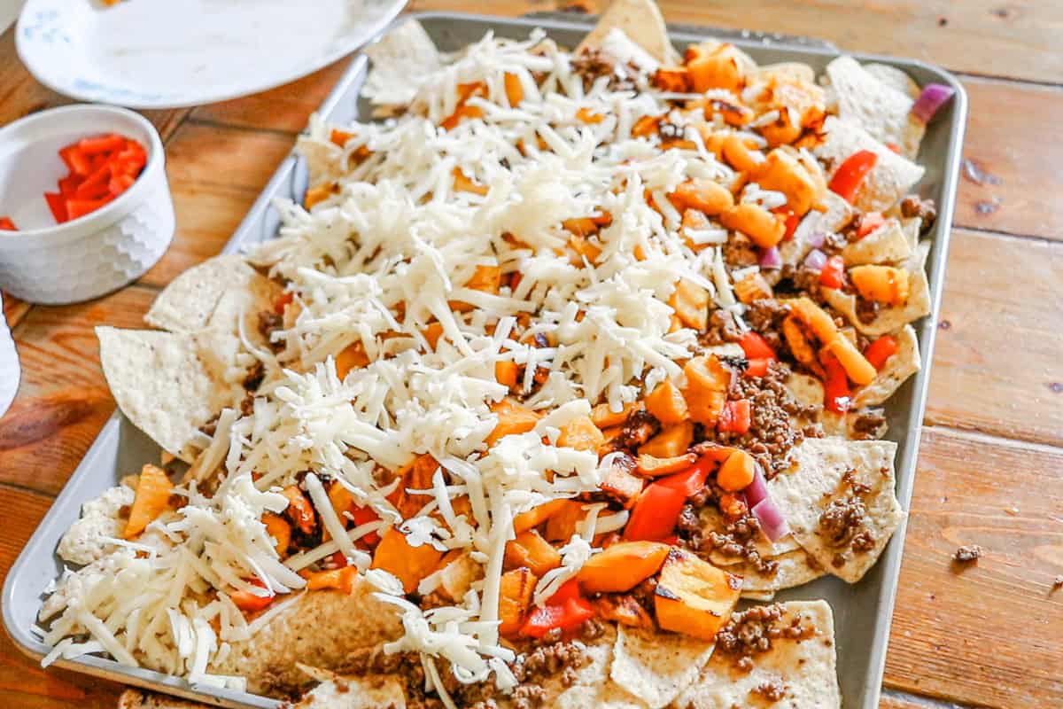 Adding the cheese to the top of the nachos.