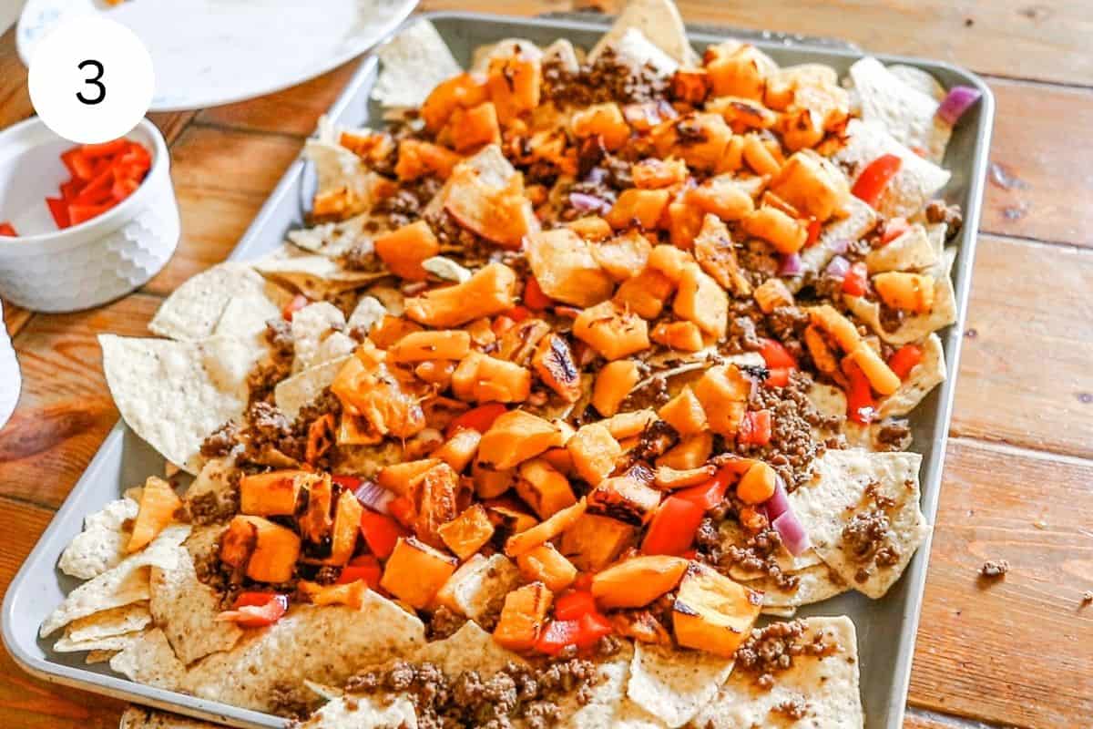 Adding the meat, peppers and diced and roasted pumpkin on top of the bed of chips.