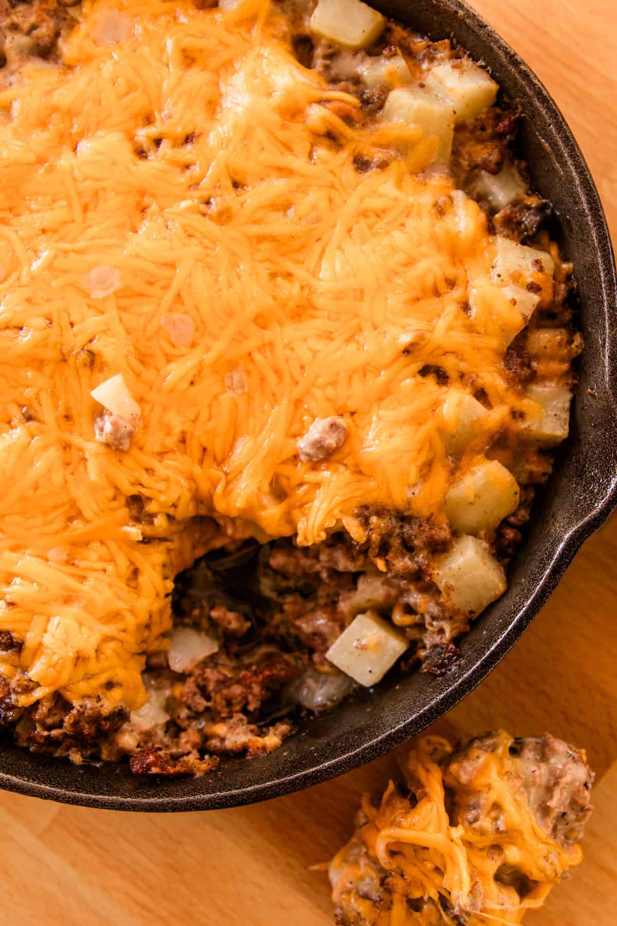 A large spoon of the casserole sitting on the table next to the dish. 