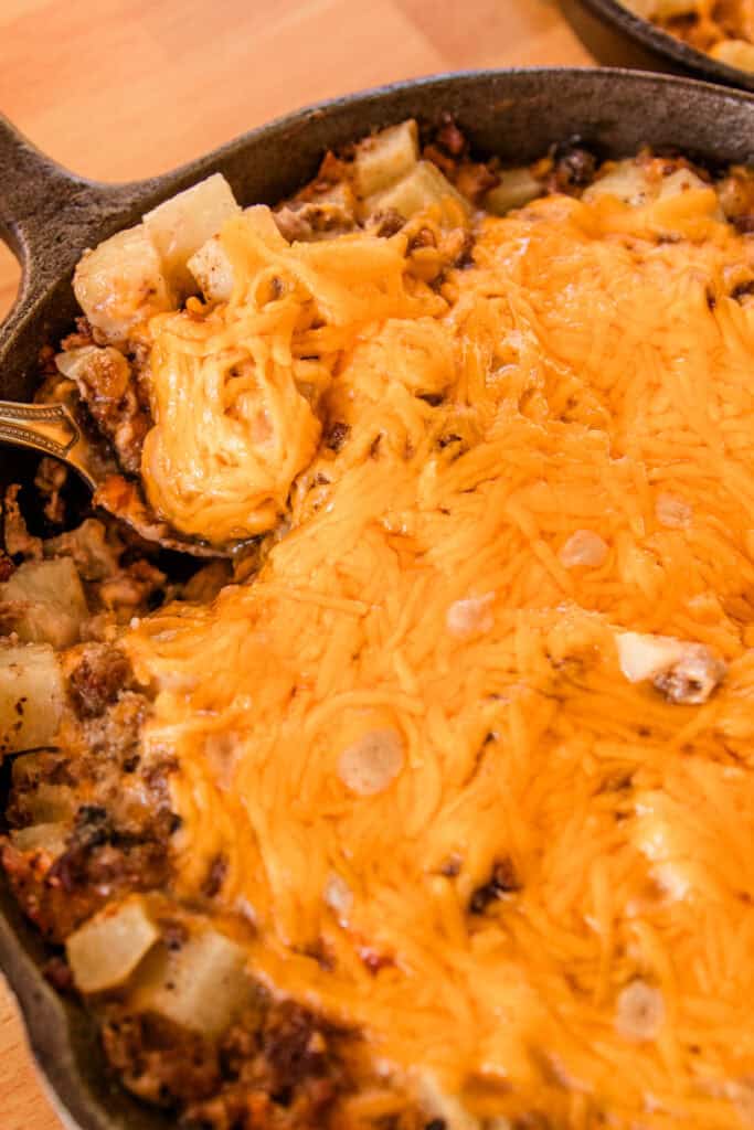 Scooping a heaping serving of the venison casserole out of the skillet.