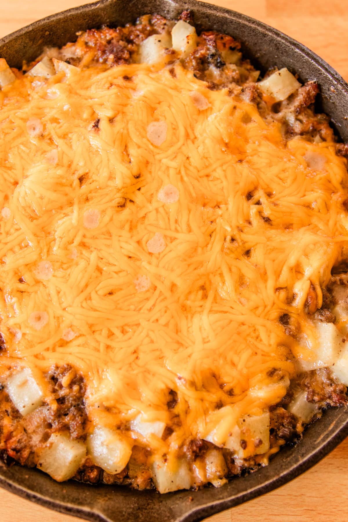 The casserole after it has baked in a large skillet with melted cheese bubbling on top. 