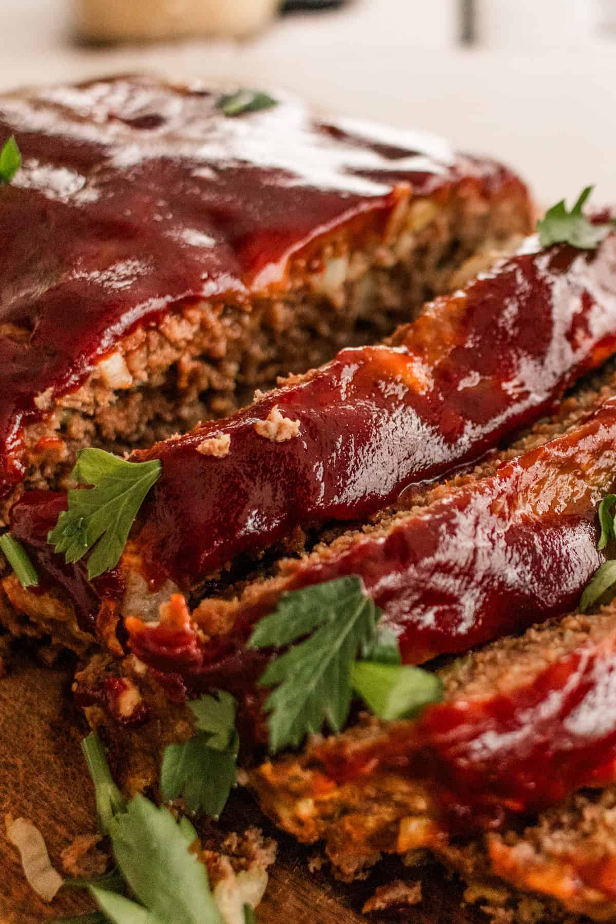 Meatloaf sitting on a wooden cutting board with fresh parsley on top. 