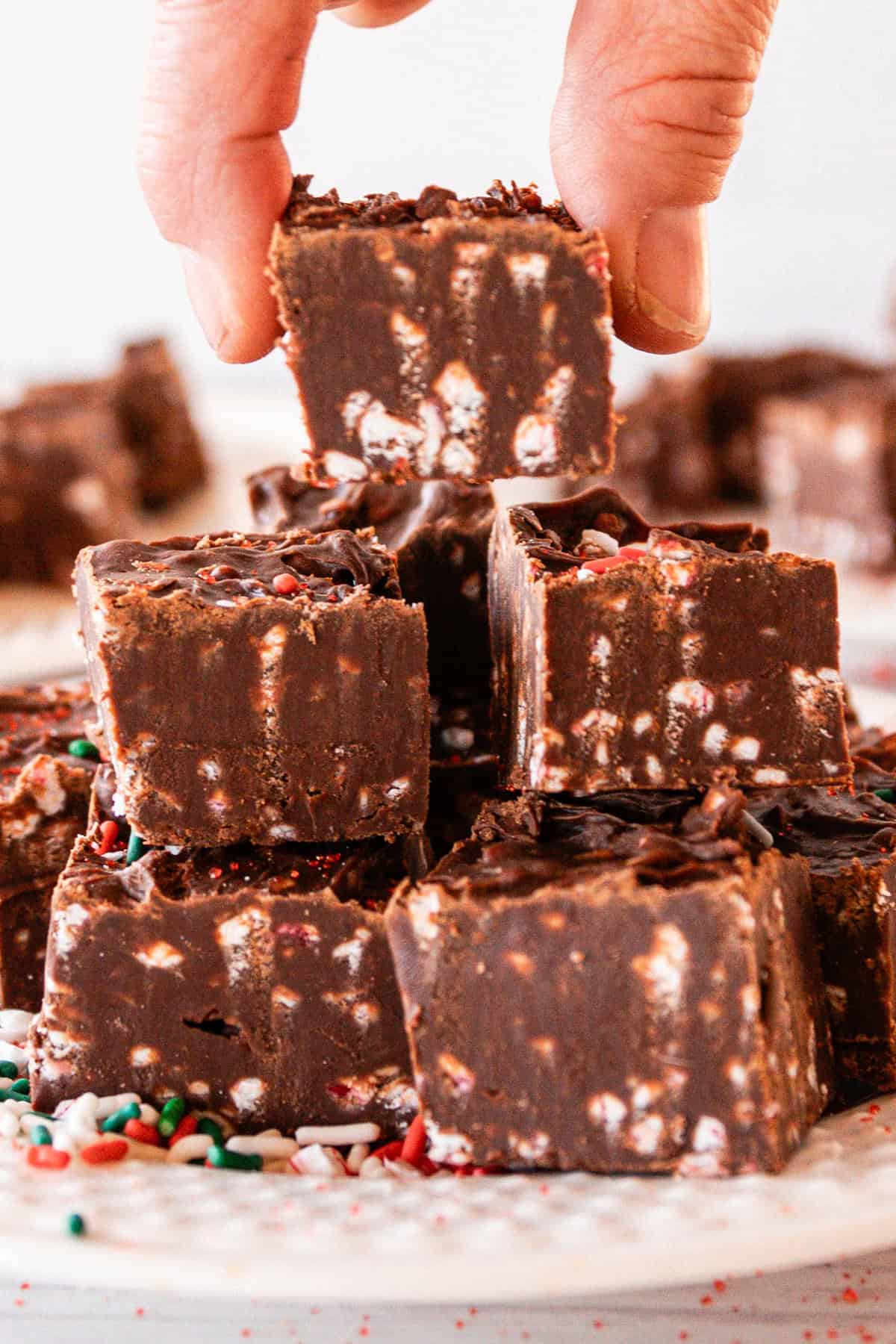 Stacking pieces of fudge on a white plate.