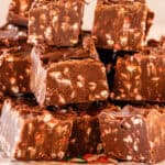 Squares of candy cane fudge stacked on a white plate.