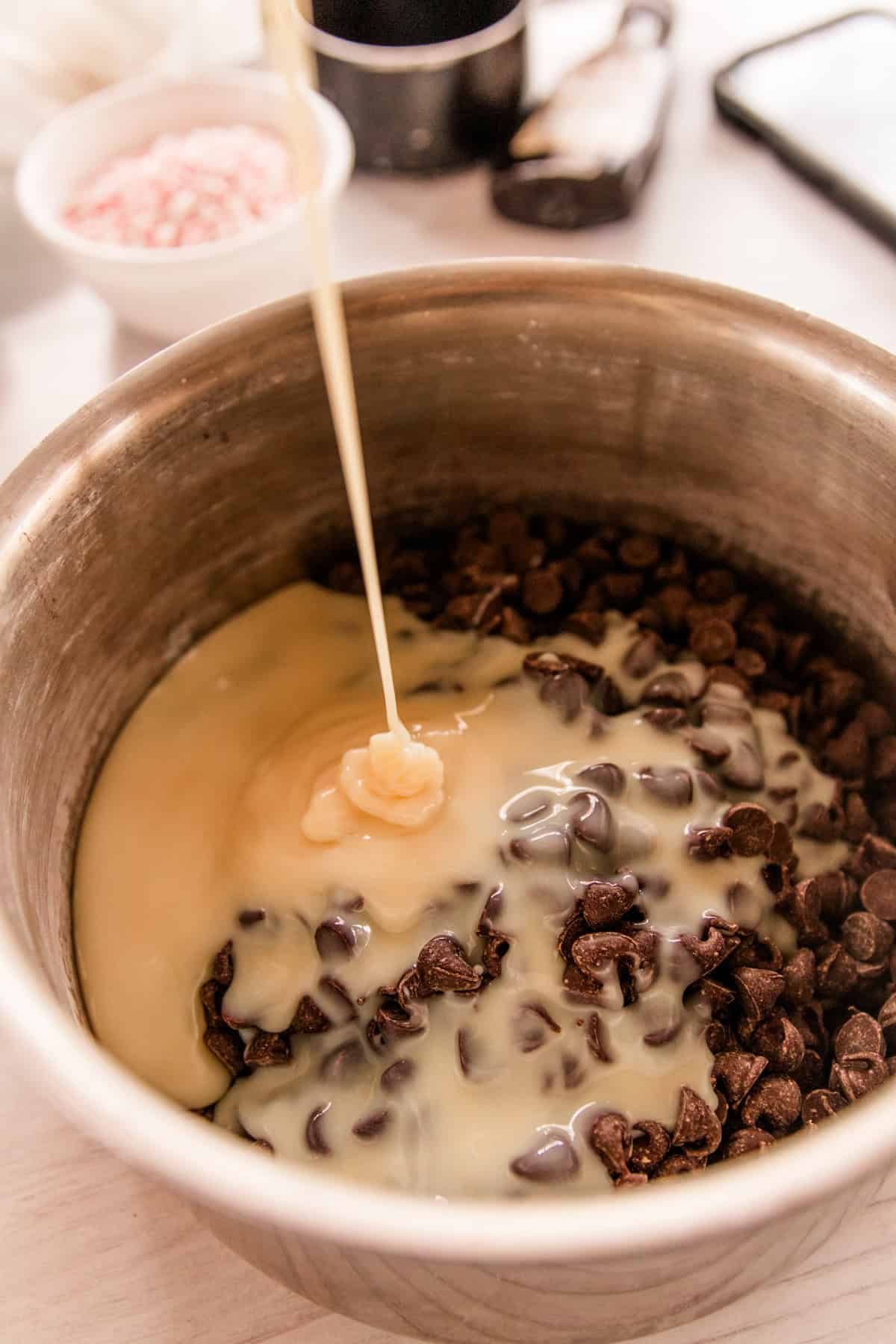 Pouring condensed milk into a bowl of chocolate chips. 