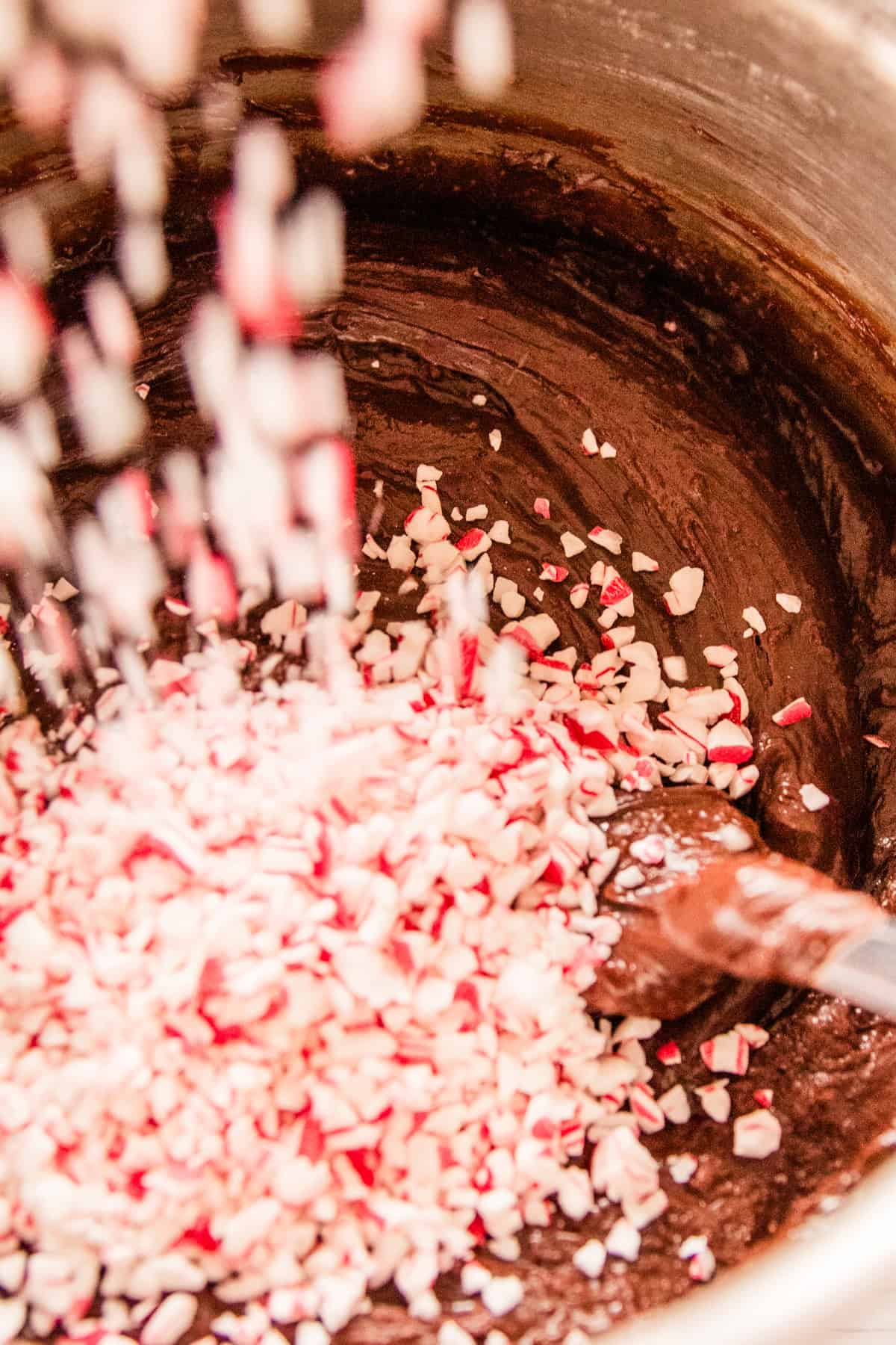 Adding crushed candy canes to the melted fudge and stirring it in with a spoon. 
