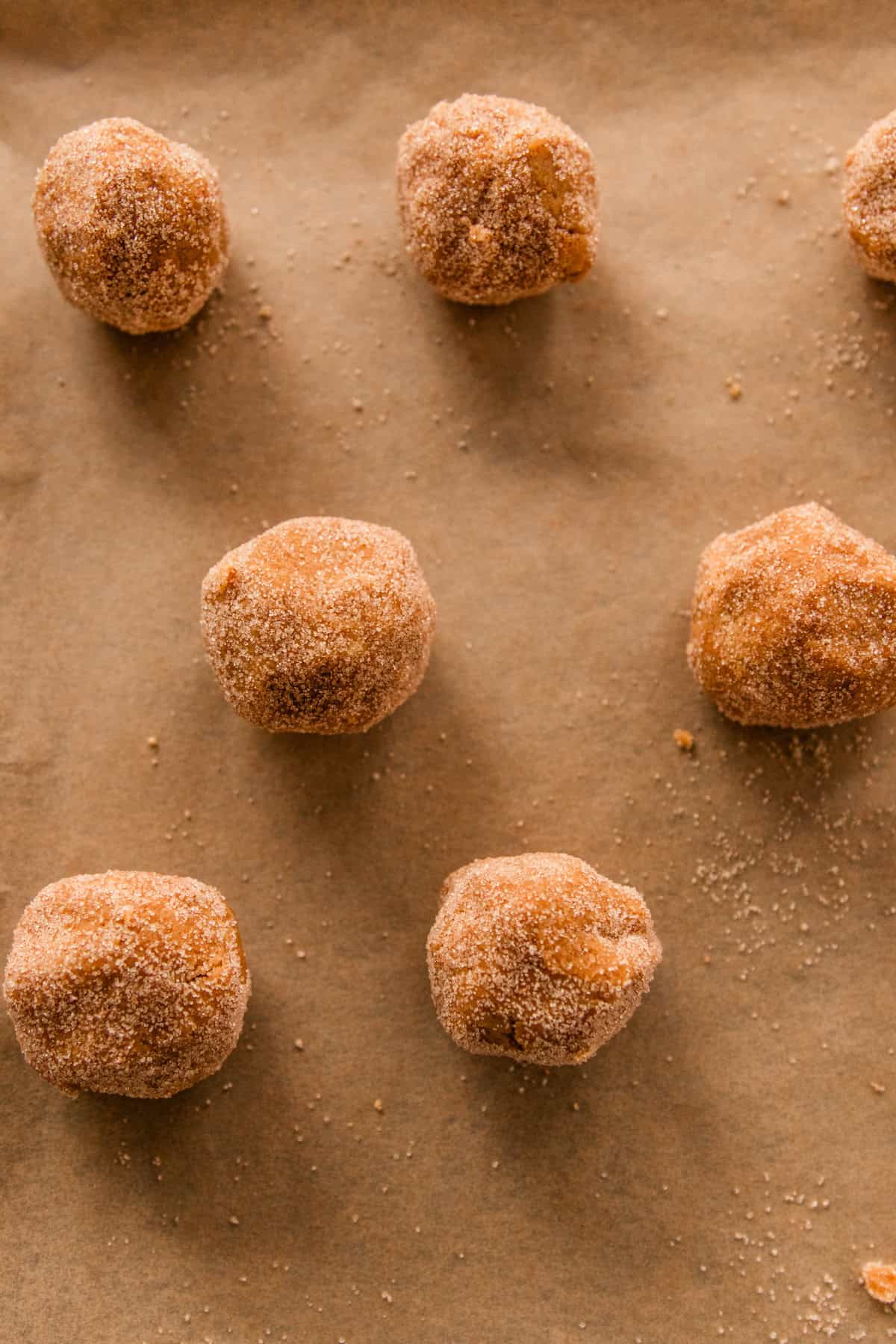 Rolling the dough into small balls and they are being placed on a cookie sheet with parchment paper. 