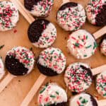 Oreo dipped christmas cookies with popsicle sticks and christmas colored sprinkles.