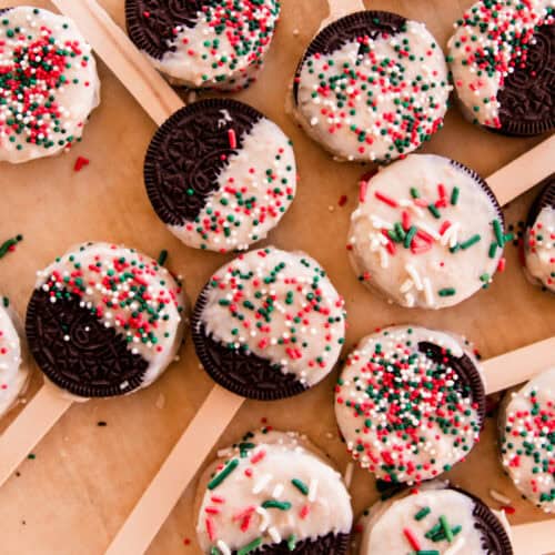 Oreo dipped christmas cookies with popsicle sticks and christmas colored sprinkles.