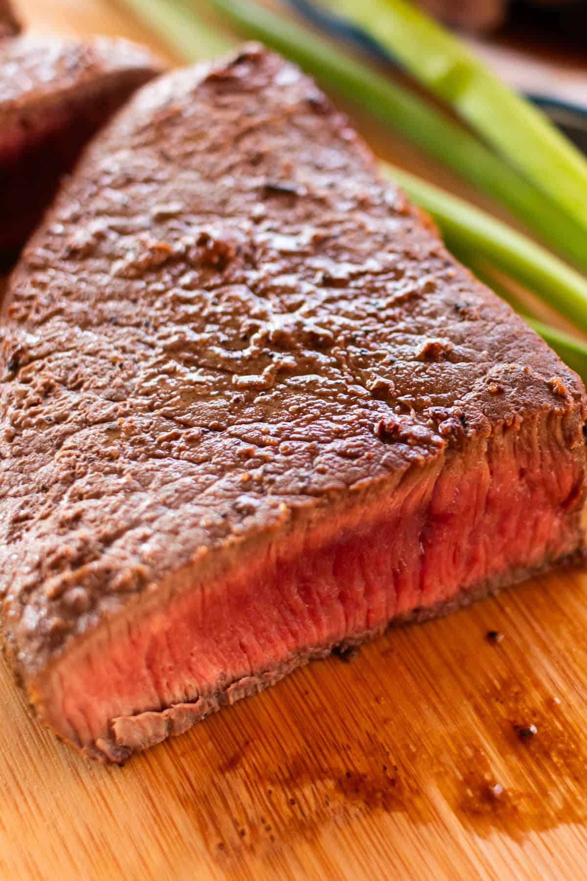 Rare cooked venison steak sliced down the middle on a wooden table. 