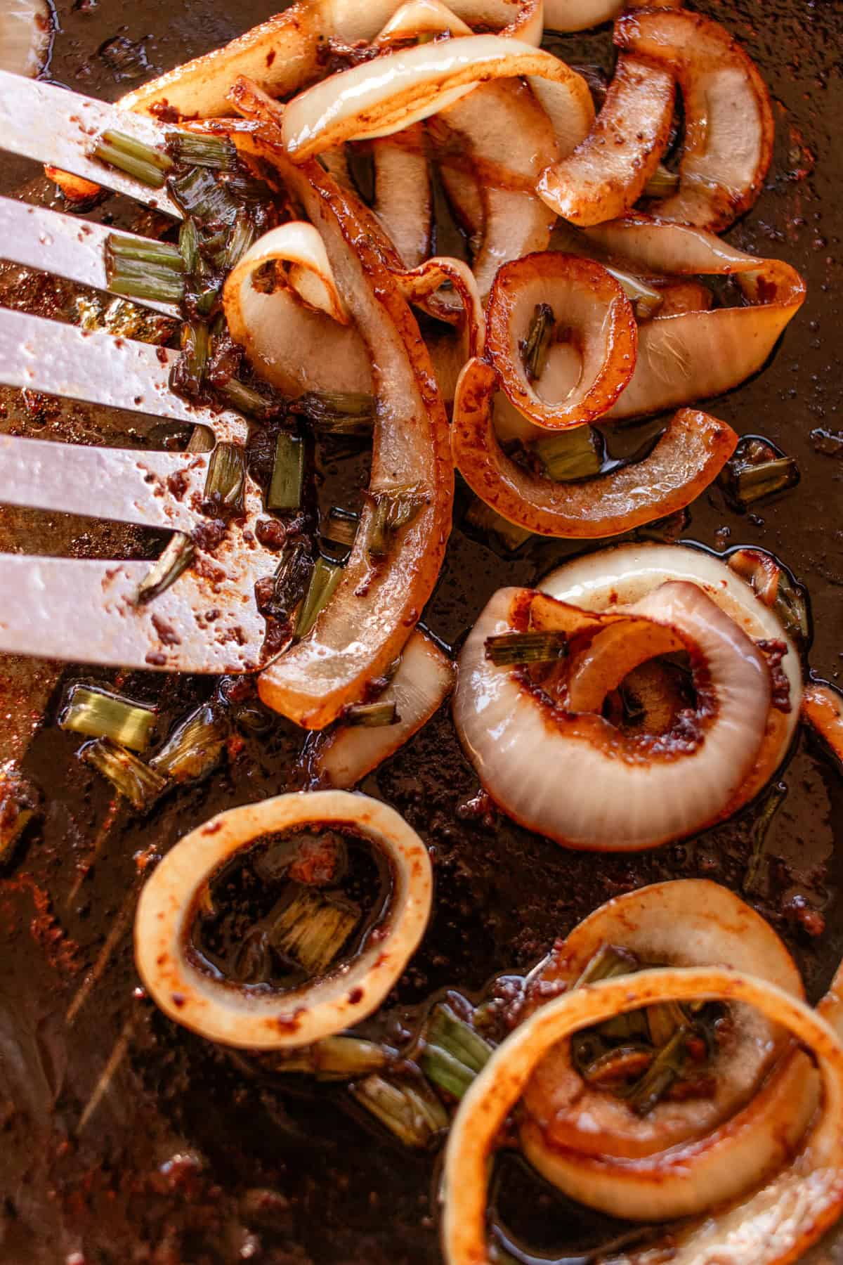 Moving the onions around in a hot skillet with a metal spatula. 