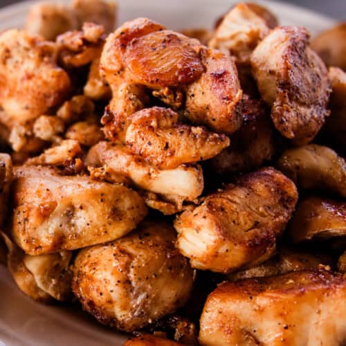 Pile of cajun chicken bites on a white plate.